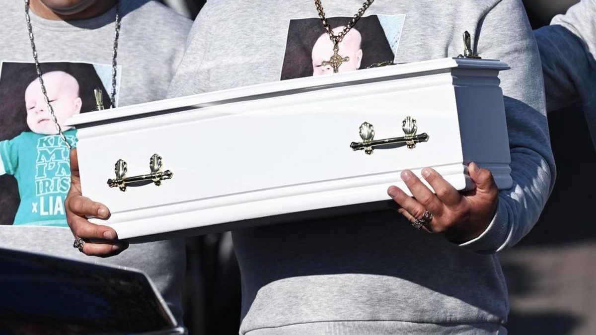 Heartbroken father of baby stabbed to death fights back tears as he cradles his baby boy’s tiny coffin at funeral